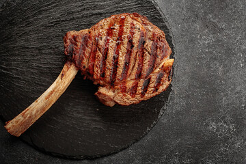 Juicy Grilled steak on the bone on a black round stone
