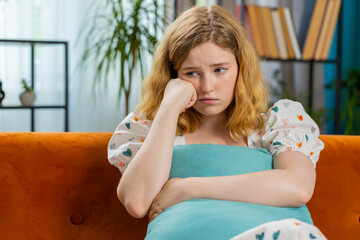 Sad lonely woman sits at home room looks pensive thinks over life concerns or unrequited love suffers from unfair situation. Alone girl problem break up depressed feeling bad annoyed burnout. Vertical