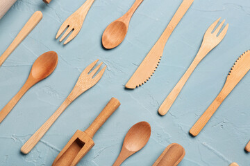 Wooden knives, forks and spoons on blue background