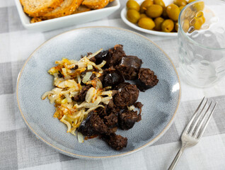 Spanish blood sausage morcilla served with grilled onion on plate