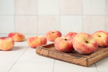 Wooden board with sweet fig peaches on white tile background