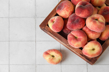 Wooden box with sweet fig peaches on white tile background