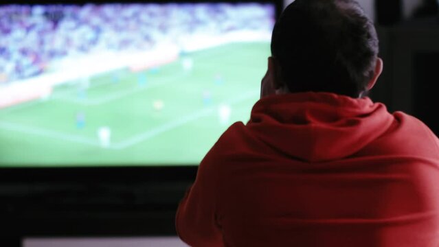 Intense Football Watching: Man on Sofa Emotionally Reacts to Near Goal on TV