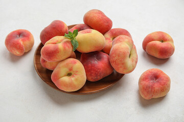 Wooden plate with sweet fig peaches and mint on white background