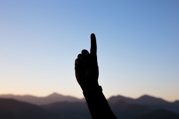 silhouette of hands in the shape of a number one with a beautiful colorful late afternoon sky in Rio de Janeiro.