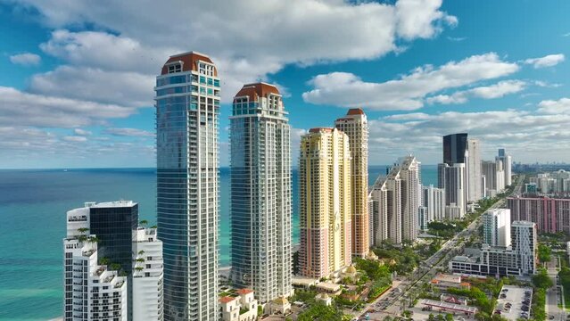Expensive highrise hotels and condos on Atlantic ocean shore in Sunny Isles Beach city and busy street traffic. American tourism infrastructure in southern Florida