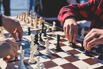 Chess tournament, kids and adults participate in chess match game outdoors in a summer sunny day,...