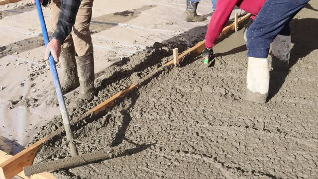 Wet concrete placement pour pave driveway at construction site by new home.