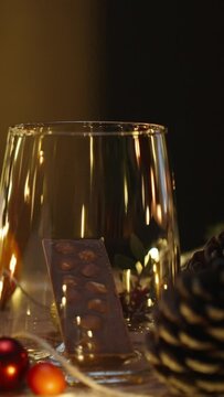 I make a drink from chocolate and cocoa. Christmas table with decorations and sweets. Candles and a garland are burning. Slow motion.