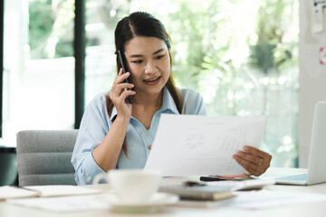 Smiling businesswoman talking on smartphone while waiting client in office