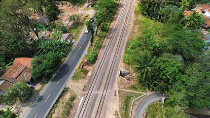 Aerial drone view of highway and railroad tracks among green trees and mountains