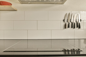 a kitchen with white tiles on the wall and black counters in the center of the photo is blurry