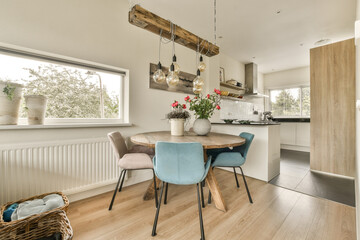 a kitchen and dining area in a house with wood flooring, white walls, wooden table and blue chairs