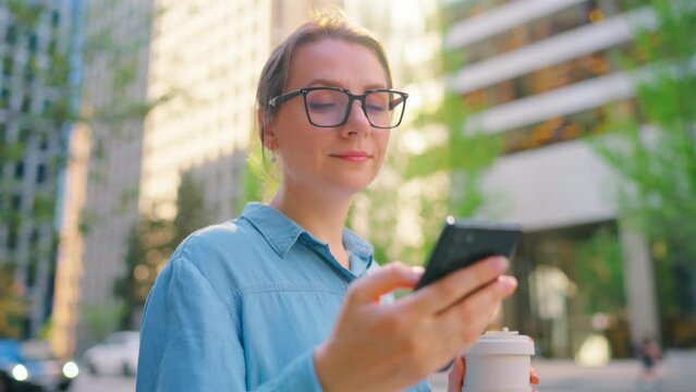 Caucasian woman in glasses walking around the city and using smartphone
