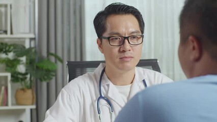 Close Up Of Asian Male Doctor With A Fat Male Patient In Clinic, Sitting At Desk, Discussing About The Results Of Medical Check Up, Giving Bad News, Encouraging A Patient
