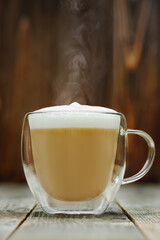 hot cappuccino in glass cup on grey wooden table