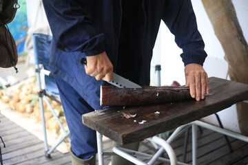 	収穫した真竹のタケノコを切る男性