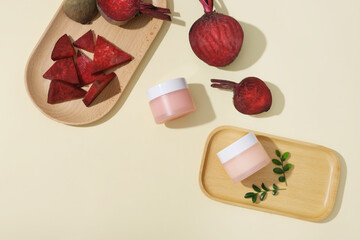 Wooden dishes featured beetroot cut in slices and an unbranded pink jar. Beetroot (Beta vulgaris) can help you eliminate dark circles under your eyes