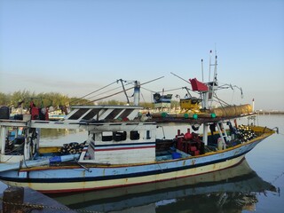 
a dominant blue boat anchored in a traditional harbor on the coast of Paiton, Probolinggo, East Java, Indonesia