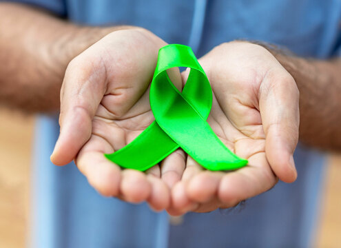 Green ribbon put in human's hands World mental health day