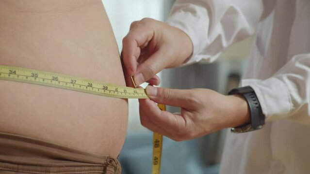 Close Up Side View Of Male Doctor'S Hands Using Tape Measuring Fat Male Patient'S Waist
