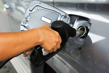 Fototapeta premium Man's hand is inserting a gas pump nozzle in a fuel tank, Car refueling on the petrol station, Oil and gas demand concept
