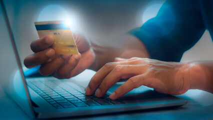 Hands holding credit card and using laptop. Digital money transfer, banking and e commerce concept.