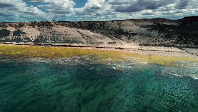 cliff front of the beach shhoting with a drone in the peninsula vald&eacute;s , argentina. The water is transparent and the colors of the seeweeds are green and yellow.