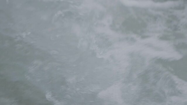 Ocean waves splashing on the surface of the sea. Far from shore, boat cruising in gloomy wether