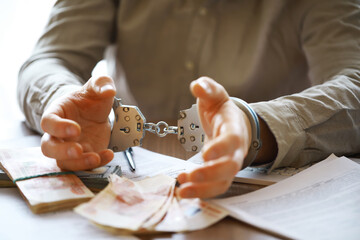 Hands in handcuffs behind, holding five thousand rubles. Concept of corruption