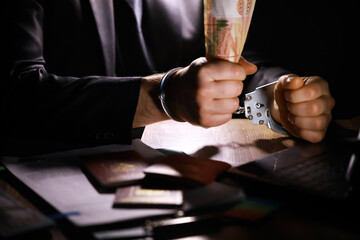 Hands in handcuffs behind, holding five thousand rubles. Concept of corruption