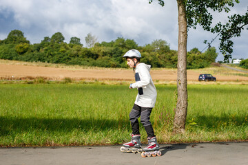 Active school boy skating in summer park, healthy lifestyle for children. Happy teenager with...