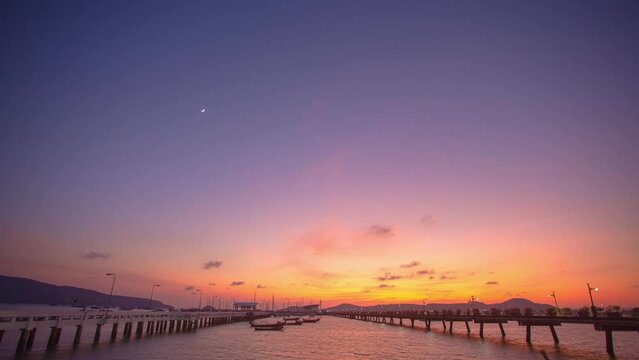 time lapse first light in the morning have sweet pink and purple in blue sky above Chalong pier..sweet yellow sunrise color light rays and other atmospheric effects. .gradient sky.pier background