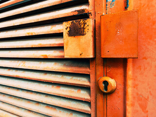 Old metallic industrial doorway painted in orange with corrosion marks