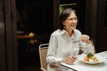 Cheerful senior woman having lunch in cafe
