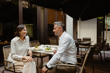 Two mature business partners having lunch in cafe