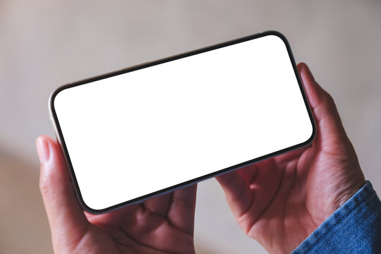 Mockup image of a woman holding and using mobile phone with blank desktop screen