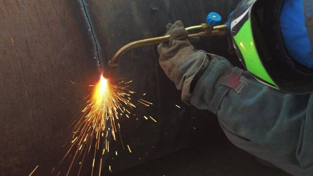 Video. Welder cuts steel pipe with gas torch. Work of autogenous welder. Close-up rear view. Authentic workflow.