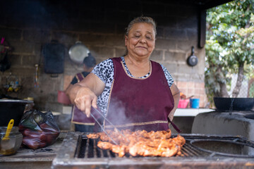 Latin woman cooking meat on a grill