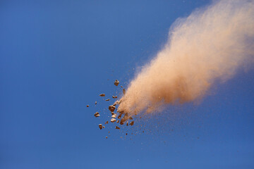 Fototapeta premium Flying rock breaking apart leaving dust trail in sky