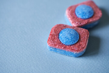 Dishwasher tablets in soluble coating on blue background. Space for copying text.