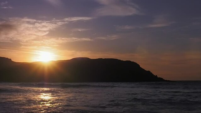 Static shot of the sun setting over the headland at Dail Beag beach on the Isle of Lewis, part of the Outer Hebrides of Scotland.