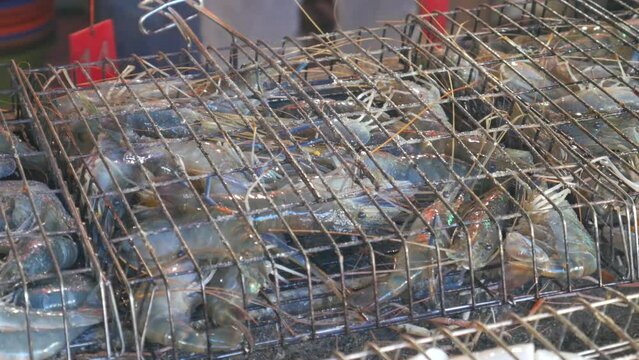 blue live raw fresh river prawn in metal cage on hot charcoal cooking in thailand