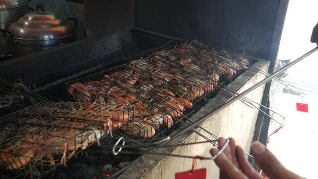 grill cooking river prawns in metal cage on hot charcoal at thailand fish market