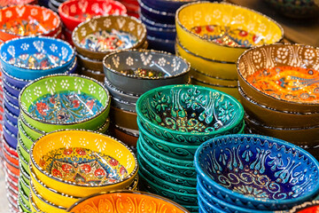 Naklejka premium Stack of classical traditional Turkish ceramics, handmade colorful dishes at the Istanbul street Bazaar. Istanbul, Turkey souvenirs. Selected focus, copy space