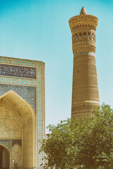 Obraz premium Kalyon minar great minaret and Kalon mosque designed with traditional tile ornaments and text from Q'ran (verses from Koran holy book in arabic language). Retro film stylisation. Buhkara, Uzbekistan.