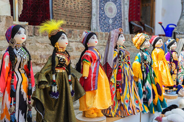 Dolls dressed in traditional uzbek costumes. Traditional souvenir puppet from painted mashed paper (papier mache). Close up, selected focus. Bukhara (Buxoro), Uzbekistan. Souvenir and gift concept
