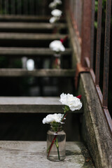 Fototapeta na wymiar White flowers in a jar. Decoration leading on some old wooden stairs at a wedding venue in Germany