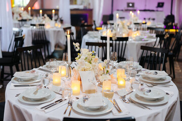 Beautiful table setting and decorations at a wedding. Wedding venue with beautiful decor, flowers, cutlery and lights