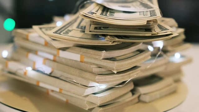 Many packs of 100 dollar bills folded in pyramid on a rotating surface close up. Big money, cash income and profit.